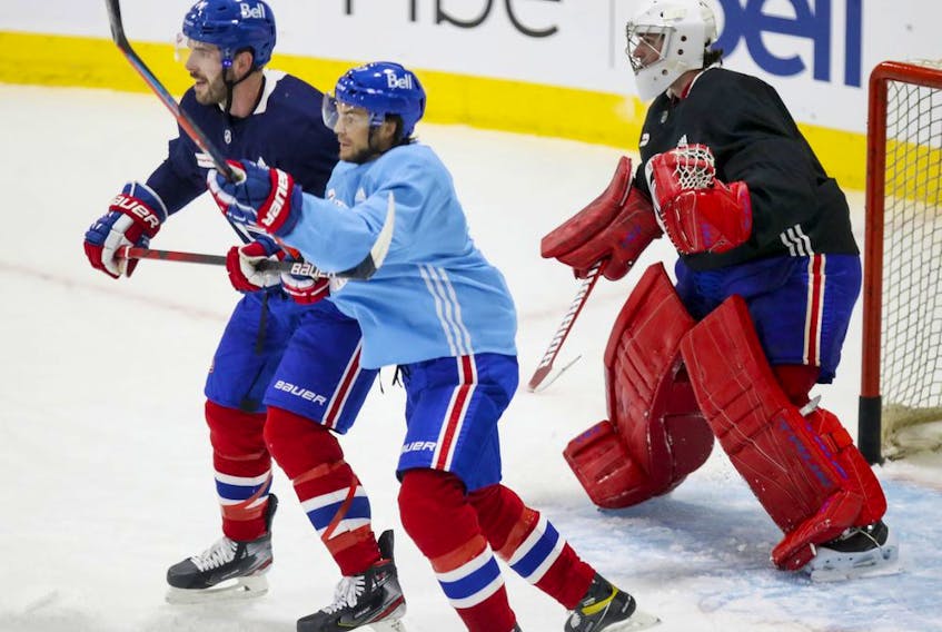 Canadiens newcomers Joel Edmundson, left, and Michael Frolik battle for position in front of goalie Carey Price during training-camp practice Monday at the Bell Sports Complex in Brossard on Jan. 4, 2021.