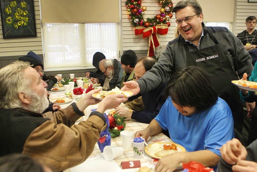 Then-Montreal Mayor Denis Coderre, right, serves a meal in Jan. 10, 2016, to Murray Nicol, left, at the Accueil Bonneau shelter during the annual diner des rois. 