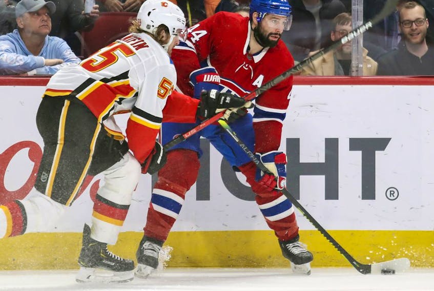  Montreal Canadiens’ Nate Thompson looks to pass the puck under pressure from Calgary Flames’ Noah Hanifin during third period in Montreal on Jan. 13, 2020.