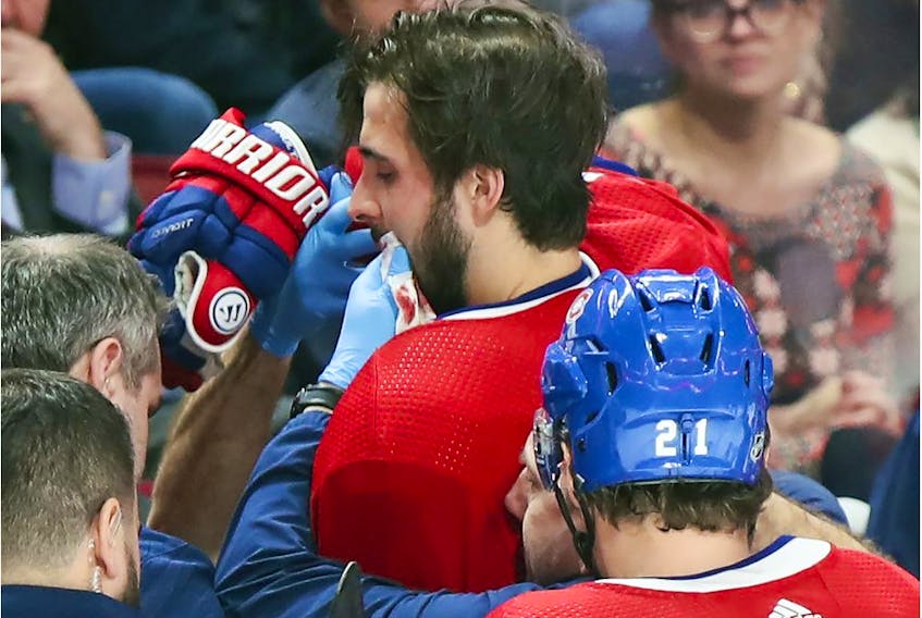 The Canadiens' Phillip Danault is helped to the dressing room after being hit in the mouth with a shot from teammate Tomas Tatar during NHL game against the Arizona Coyotes at the Bell Centre in Montreal on Feb. 10, 2020.