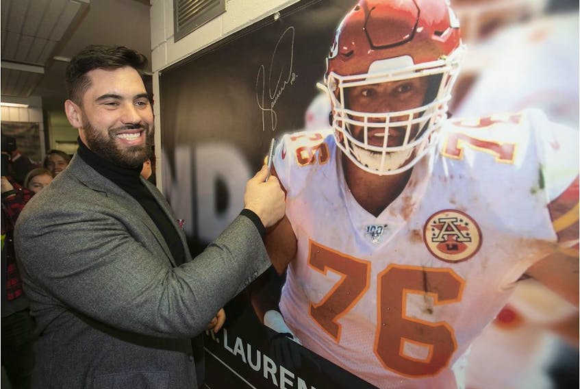 Laurent Duvernay-Tardif is all smiles after signing banner of himself that was unveiled at the McGill sports centre on Feb. 12, 2020 after he helped the Kansas City Chiefs win the Super Bowl.