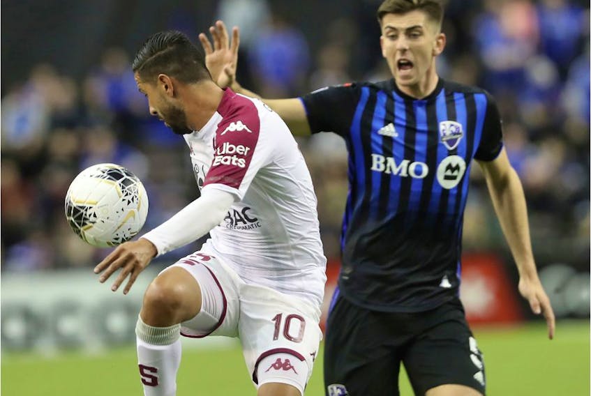  Deportivo Saprissa’s Marvin Angulo keeps ball away from Impact defender Luis Binks during first-half CONCACAF Champions League action at Olympic Stadium Wednesday night.