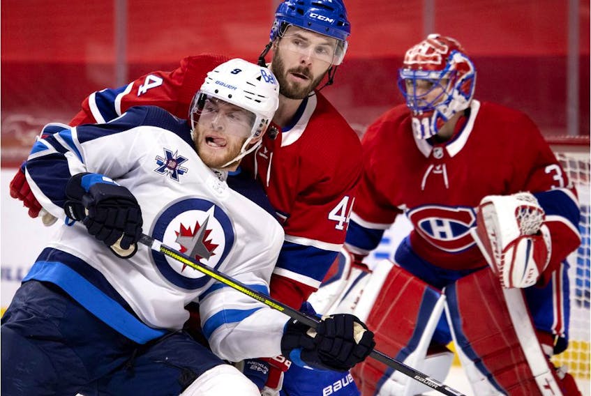 Winnipeg Jets centre Andrew Copp (9) leans into Montreal Canadiens defenseman Joel Edmundson (44) as Montreal Canadiens goaltender Carey Price (31) follows the play during NHL action in Montreal on Saturday, March 6, 2021.