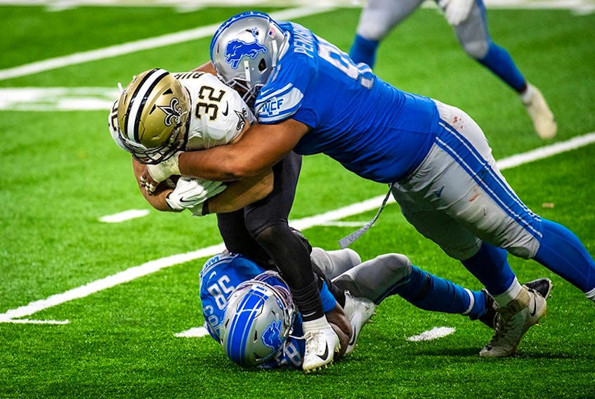 Michael Burton of the New Orleans Saints is tackled by a pair of Lions.