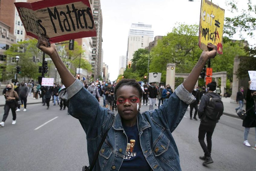 Young protesters hold signs during anti-racist and anti-police brutality demonstration in Montreal on May 31, 2020.