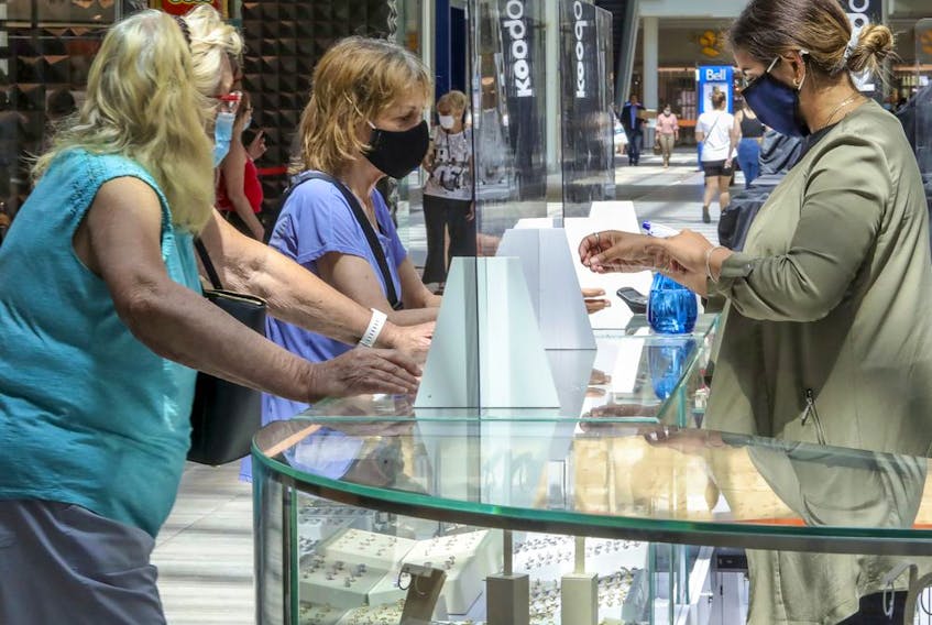 Mona Mansur, right, wears a mask behind a plexiglass barrier at her Arabella jewelry kiosk at Fairview Pointe Claire shopping mall on Friday, June 19, 2020.
