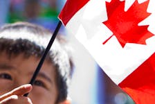A new Canadian waves the flag during a citizenship ceremony. Most Canadians don’t want the kind of overheated immigration conflicts that have occurred in some countries.