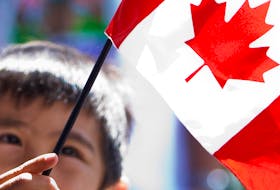 A new Canadian waves the flag during a citizenship ceremony. Most Canadians don’t want the kind of overheated immigration conflicts that have occurred in some countries.