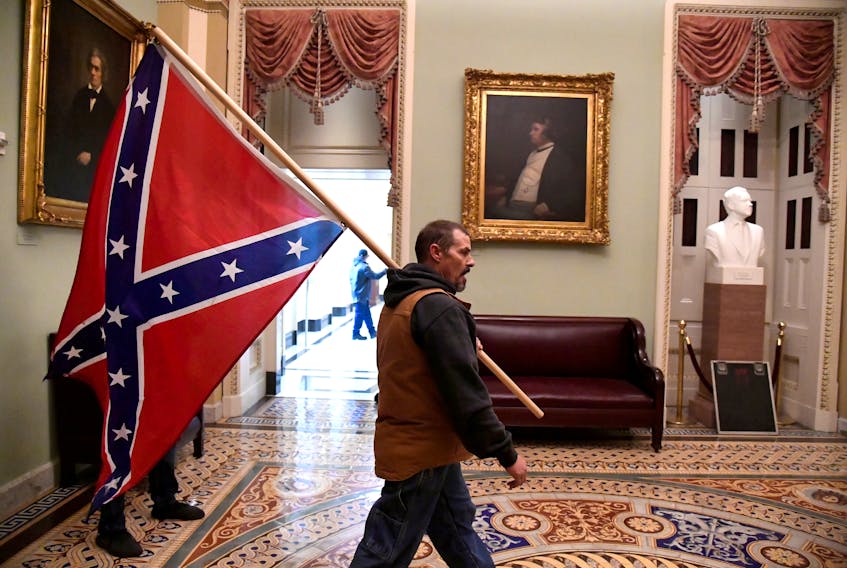 A supporter of President Donald Trump carries a Confederate battle flag on the second floor of the U.S. Capitol near the entrance to the Senate after breaching security defenses. REUTERS/Mike Theiler