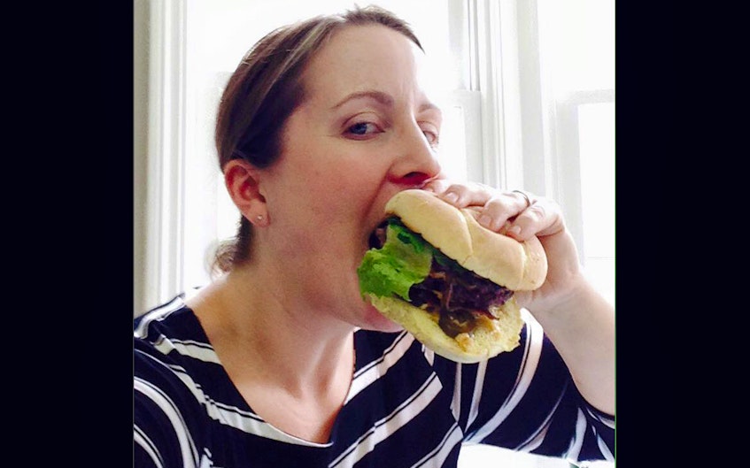 Jill Forse digs into a burger at the Port Pub in Port Williams, Nova Scotia as part of the Annapolis Valley’s Burger Wars, which is held each April as a fundraiser for Campaign for Kids.