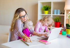 A woman works from home while trying to attend to her children in the new era of remote workplaces and social distancing.