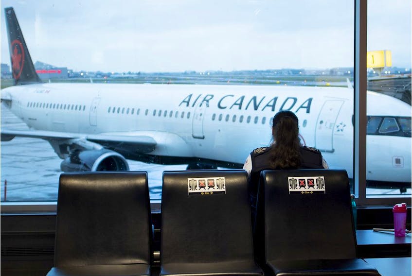 MONTREAL, QUE.: July 8, 2020-- An airport security guard takes her break alone on a bank of seats marked with Covid-19 social distancing stickers at Pierre Elliott Trudeau Airport in Montreal on Wednesday July 8, 2020.