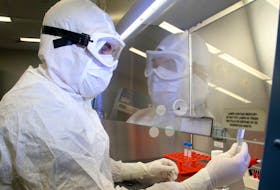 Manufacturing Associate Leon Barbeau looks at a sample under the clean hood in the Bio Therapeutics lab's virus manufacturing centre at the The Ottawa Hospital.