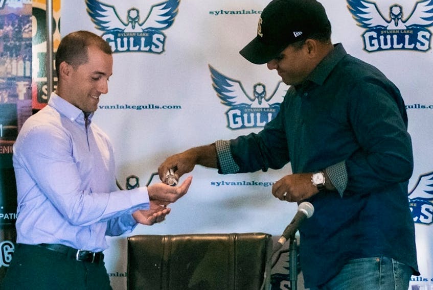 Sylvan Lake Gulls head coach Jason Chatwood, left, gets a shot of hand sanitizer from team general manager Aqil Samuel during a recent media event at Hockey Central Sports Lounge in Sylvan Lake, ahead of what is scheduled to be the club's inaugural season in the Western Canadian Baseball League this summer.