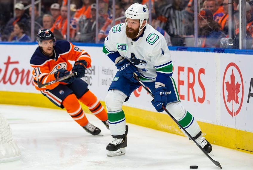 Jordie Benn of the Vancouver Canucks moves the puck as he's being pursued by Gaetan Haas of the Oilers at Rogers Place on Oct. 2 in Edmonton.