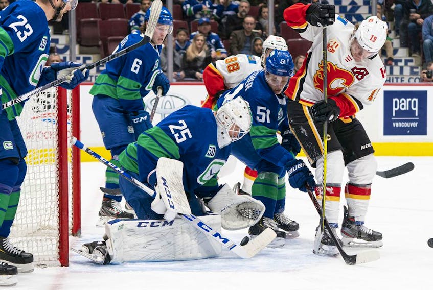 The Calgary Flames’ Matthew Tkachuk tries to put a backhand shot past Vancouver Canucks goalie Jacob Markstrom at Rogers Arena in Vancouver on Feb. 8, 2020 in Vancouver. Canucks Alexander Edler (23) and Troy Stecher (51) help defend on the play.
