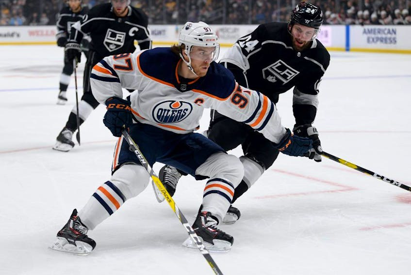 Connor McDavid #97 of the Edmonton Oilers fends off Derek Forbort #24 of the Los Angeles Kinfgs rom the puck during the first period at Staples Center on February 23, 2020 in Los Angeles, California.