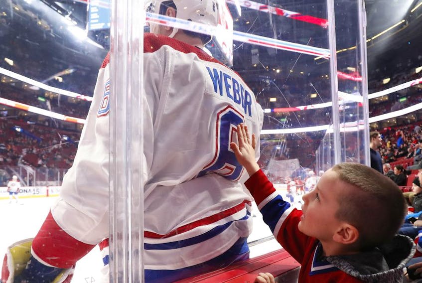 A young Canadiens fan reaches toward Shea Weber during pre-game warmup at the Bell Centre in Montreal before game against the Carolina Hurricanes on Dec. 13, 2018.