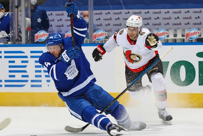 Senators' Artem Zub (right) is penalized for pulling down Morgan Rielly of the Maple Leafs during their game at Scotiabank Arena on Monday, Feb. 15, 2021 in Toronto. 