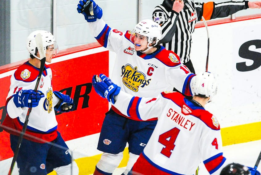 Dylan Guenther (11) of the Edmonton Oil Kings celebrates with teammates Scott Atkinson (15) and Ross Stanley (4) after scoring against the Calgary Hitmen at 7 Chiefs Sportsplex on March 27, 2021, on Tsuut’ina Nation.