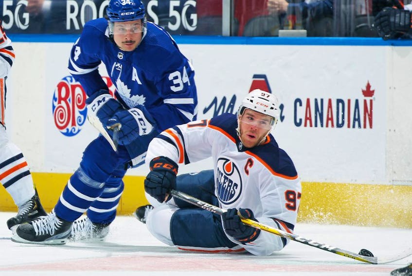 Connor McDavid (97) of the Edmonton Oilers battles for the puck against Auston Matthews (34) of the Toronto Maple Leafs during the first period an NHL game at Scotiabank Arena on March 29, 2021 in Toronto. 
