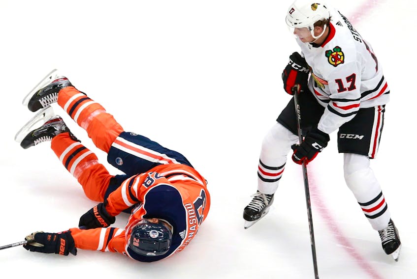 Andreas Athanasiou (28) of the Edmonton Oilers falls to the ice after colliding with Dylan Strome (17) of the Chicago Blackhawks during Game 1 of the Eastern Conference qualification round at Rogers Place on August 01, 2020.