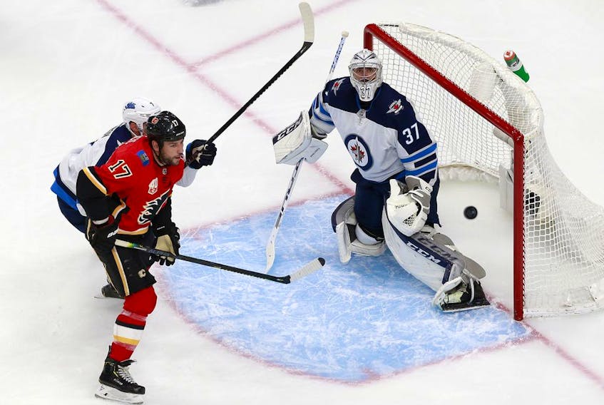 Milan Lucic #17 of the Calgary Flames takes a shot as Connor Hellebuyck #37 of the Winnipeg Jets defends in Game One of the Western Conference Qualification Round prior to the 2020 NHL Stanley Cup Playoffs at Rogers Place on August 01, 2020 in Edmonton, Alberta.