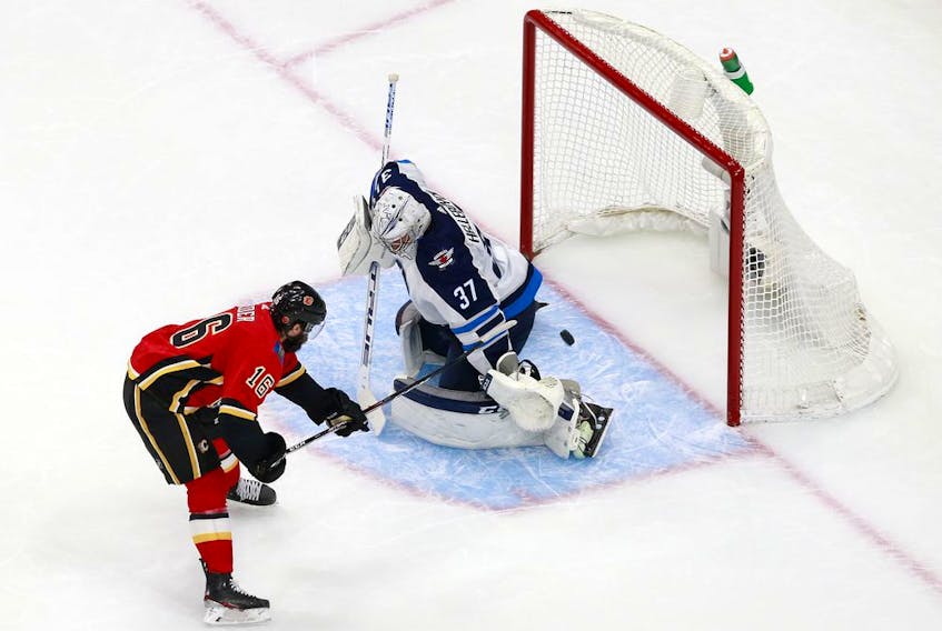 Flames forward Tobias Rieder steers a shot  on goal as Jets netminder Connor Hellebuyck defends during second-period action in Game 1 of the Western Conference Qualification Round prior to the 2020 NHL Stanley Cup Playoffs at Rogers Place late Saturday night in Edmonton. Photo by Jeff Vinnick/Getty Images.