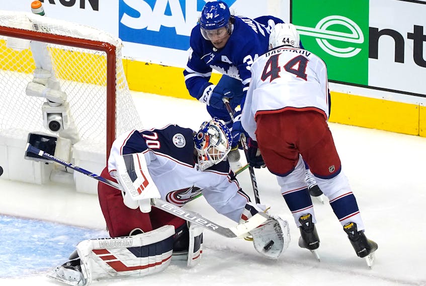 Joonas Korpisalo  of the Columbus Blue Jackets stops a shot as Leafs' Auston Matthews is kept out of harm's way by defenceman Vladislav Gavrikov during the second period of Game 1 last night at Scotiabank Arena.