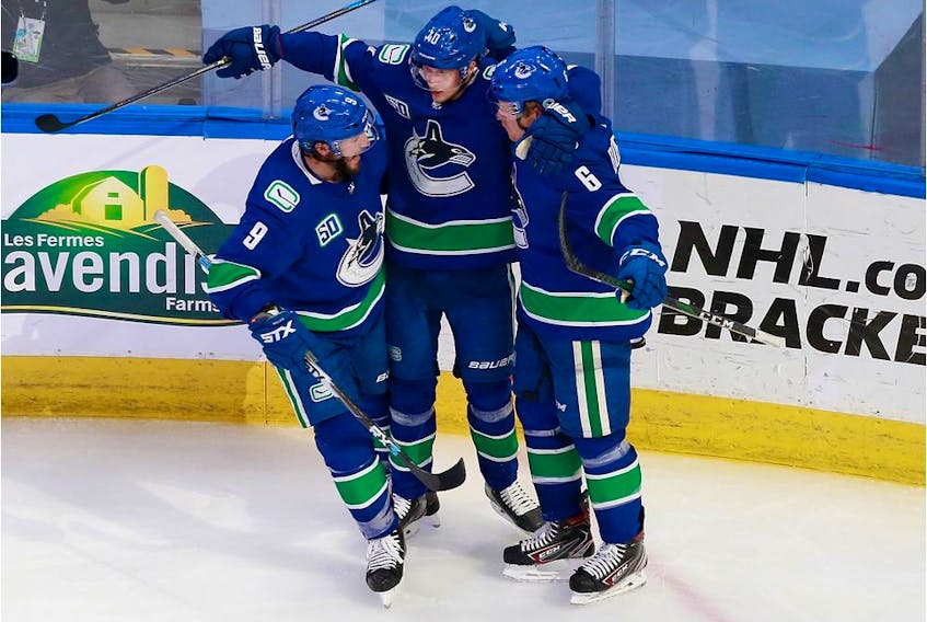 Brock Boeser of the Vancouver Canucks, right, celebrates his second-period goal on Tuesday with J.T. Miller, left, and Elias Pettersson. The Canucks tied the best-of-five qualifying series with a 4-3 win in Edmonton.
