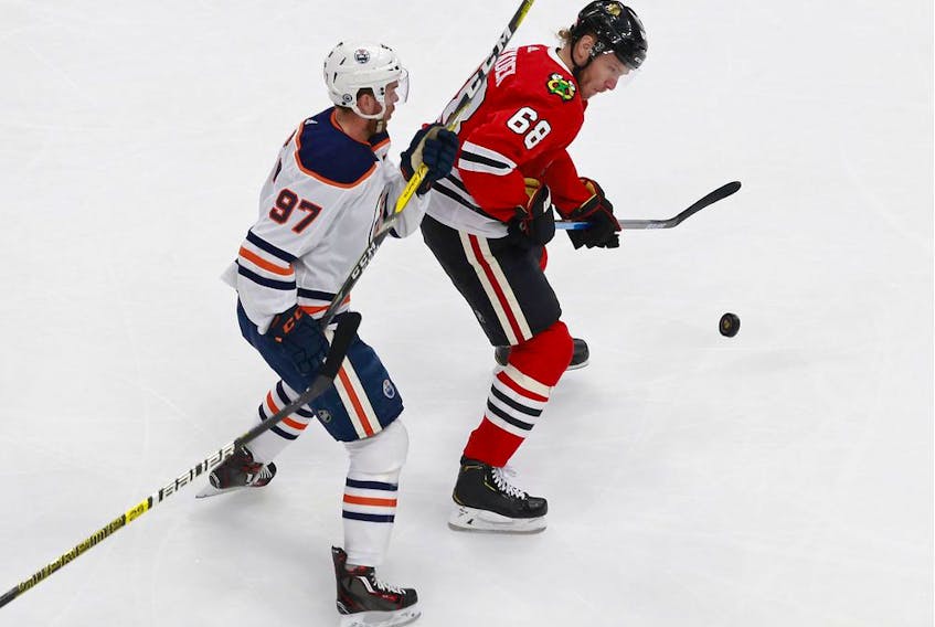 Slater Koekkoek #68 of the Chicago Blackhawks is pursued by Connor McDavid #97 of the Edmonton Oilers during the first period in Game 3 of the Western Conference Qualification Round at Rogers Place on August 05, 2020.