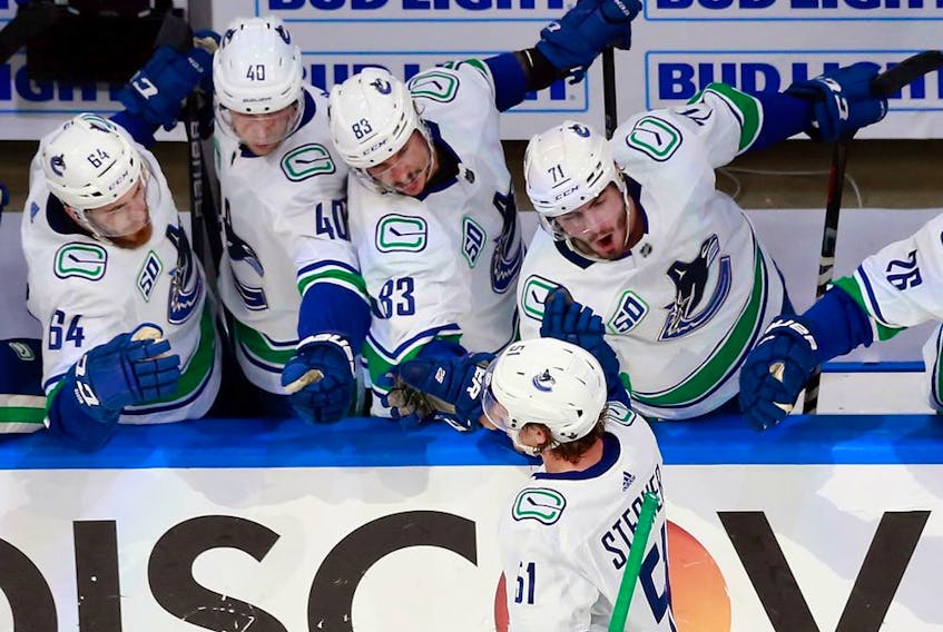 Troy Stecher of the Vancouver Canucks is congratulated by his teammates as he skates by the bench after his third-period goal against the St. Louis Blues in Game 1 on Wednesday night in Edmonton.
