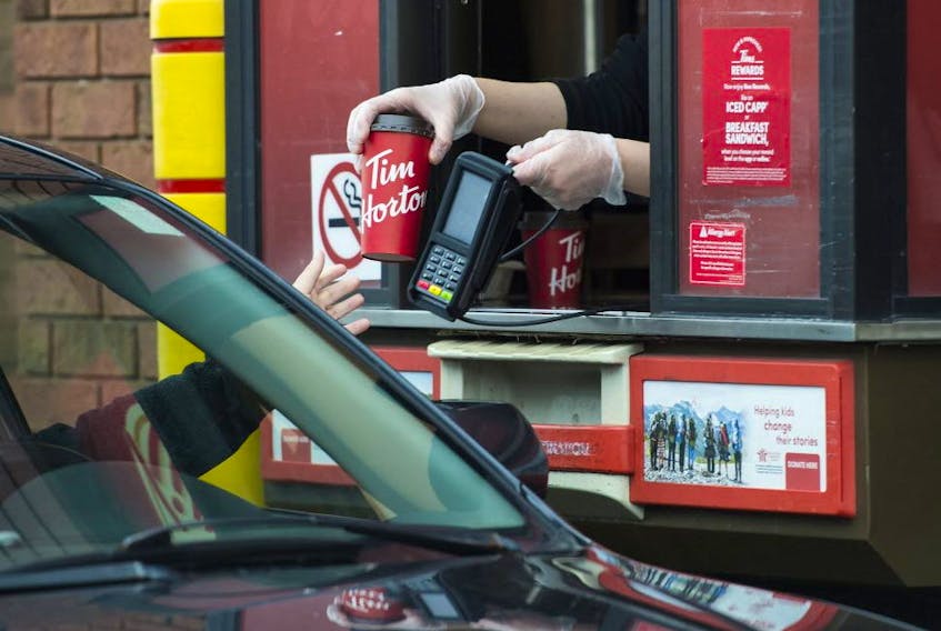  A Tim Hortons employee hands out coffee at a   drive-thru in Mississauga on March 17, 2020. 