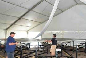 Bobby Mitchell, left, and Forrest Beaton build the stage in the tent for the 2015 P.E.I. International Shellfish Festival.