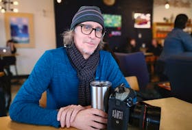 David Howells sitting in his office — a coffee shop — with his YETI mug named Greta and a camera he would never sell. Andrew Waterman/The Telegram