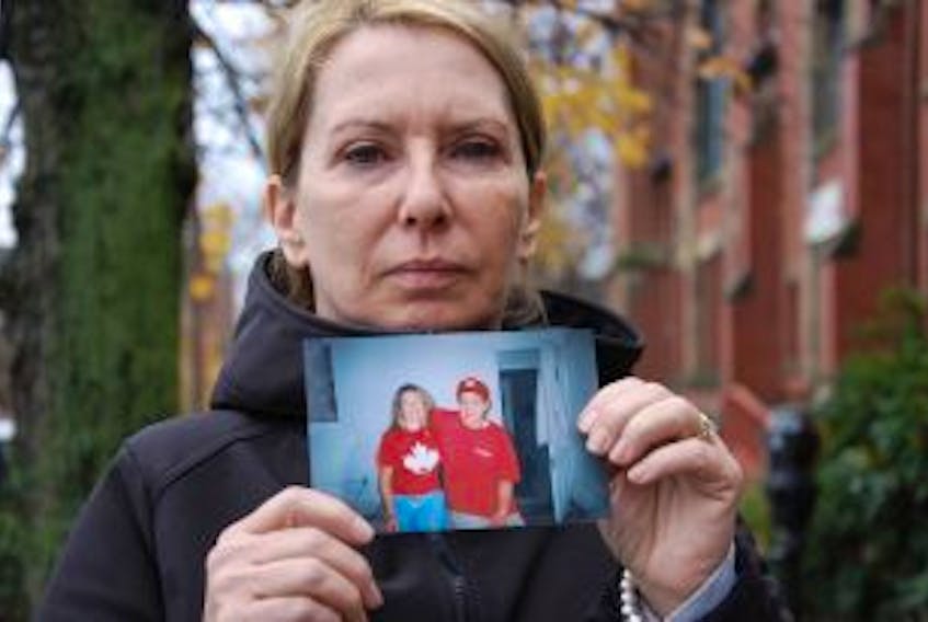 ["Dianne Young of Charlottetown holds a photo of her and son Lennon Waterman during a happier period in her son's life."]