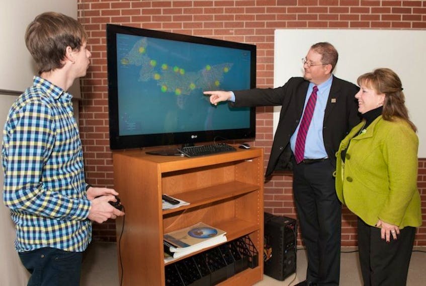 Adam Fenech, second right, director of UPEI’s climate research lab, demonstrates a new tool to demonstrate the effects of coastal erosion to P.E.I. Environment Minister Janice Sherry as Andrew Doiron, left, research assistant with the climate lab looks on.