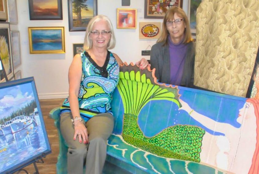 It’s been a great year for the Artisans on Main Street project in Montague which now has a permanent location for the artist collective which includes painter Lorraine Vatcher, left, and beader Nancy Oakes enjoying a Nancy Perkins-painted bench.