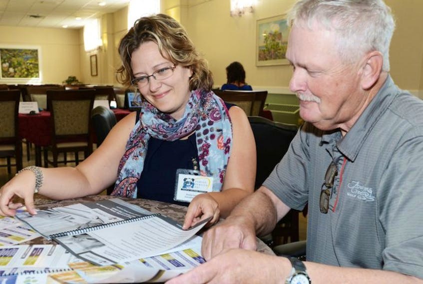 Denise Lockhart, executive director of Family Service P.E.I. and George Noble, chair of the Gulf Shore Community Health Corporation, look over a new financial literacy toolkit for seniors.
