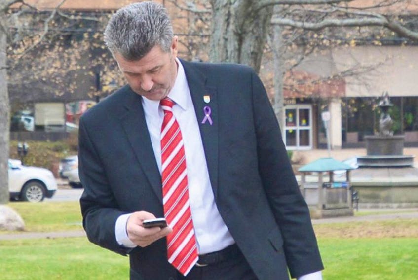 Finance Minister Wes Sheridan checks his phone on the way to the provincial legislature Wednesday afternoon.