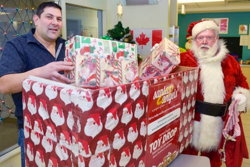Tommy Corrigan, dressed as Santa, and Ken Zakem stand next to a donation box for the Santa’s Angels at Zax Cafe. The group is still accepting donations and nominations to help provide a Christmas morning surprise to Charlottetown area families.