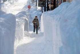 <p>The snow cuttings on Water Street in Charlottetown February 17, 2015 are over the pedestrian's head after a major blizzard left 80 centimetres of snow in Charlottetown and across the province. The province is slowly digging put after the storm on Islander Day weekend.</p>