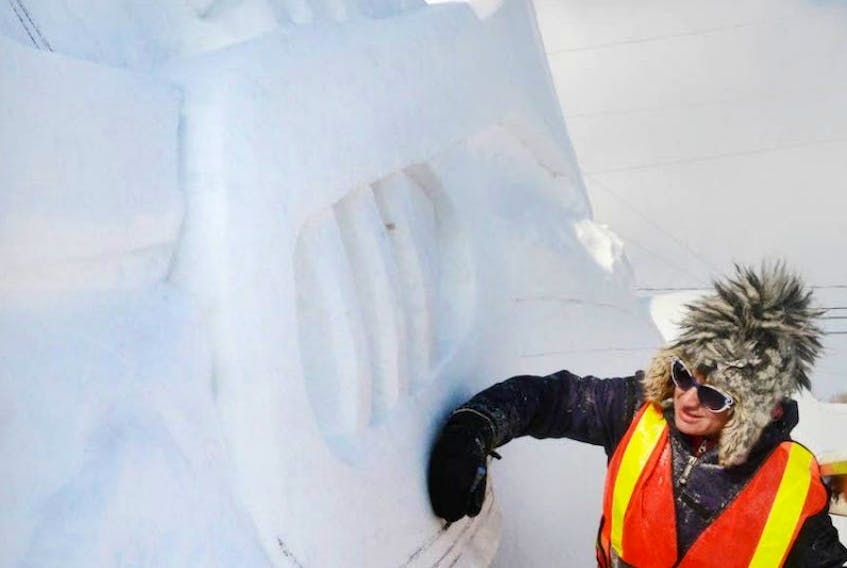 Morgan Rudluff, a snow sculptor, sketches out the outline of a trumpet for the Jack Frost Festival. This year's festival theme is music. The festival will be held this weekend.