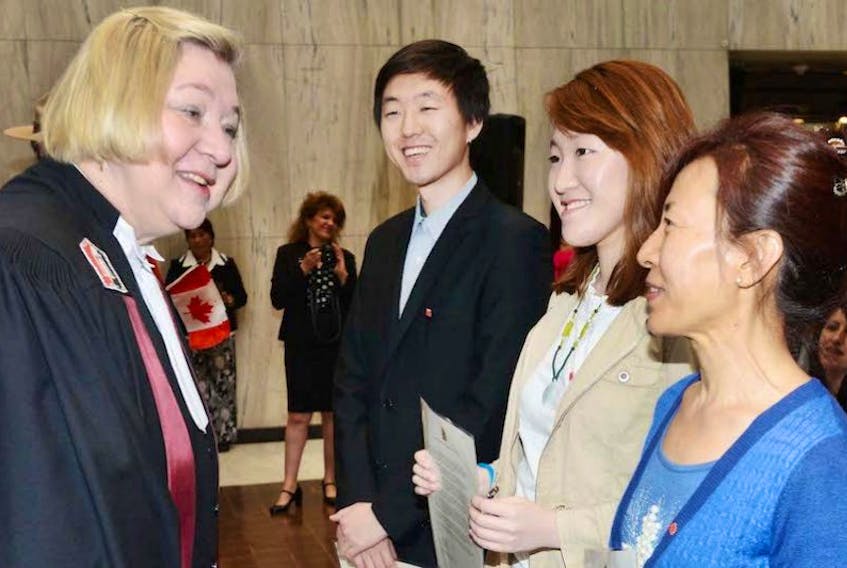 ['Citizenship judge Ann Janega chats with Soonoh Ra as her children Yuhun Hwang, second left, and Youkyung Hwang look on. The family members, all from Korea, became Canadian citizens Tuesday at a swearing in ceremony in Charlottetown.']