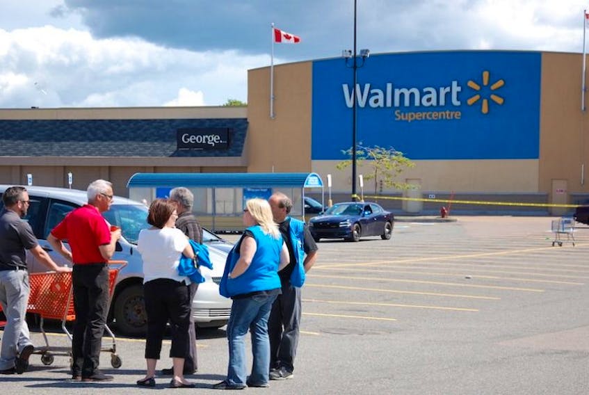 Customers and staff mingle outside the police perimeter at the Charlottetown Walmart, where a bomb threat was received Tuesday, Aug. 2, 2016.