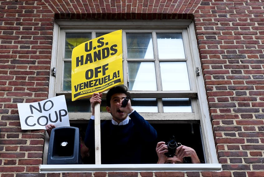 People demonstrate from the window of the Venezuelan embassy which is occupied by Nicolas Maduro supporters as Venezuelan opposition leader Juan Guido's envoy to the United States Carlos Vecchio speaks outside the embassy in Washington, U.S., May 1, 2019.