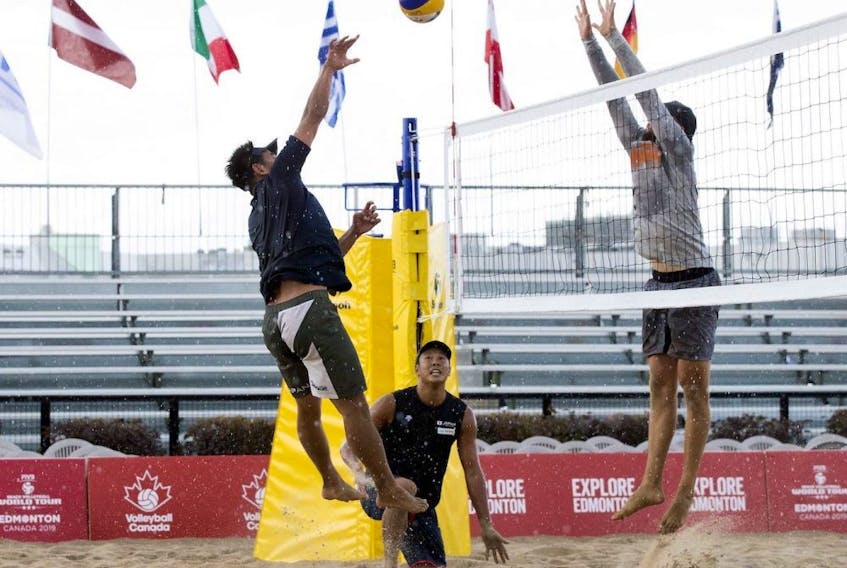 Members of Team Japan (left) and Team Canada practice in the pouring rain during the FIVB Beach Volleyball World Tour, in Edmonton Wednesday July 17, 2019. 