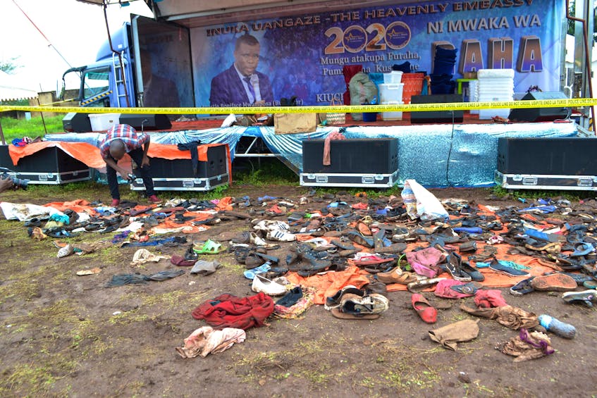 A journalist looks at the abandoned shoes and personal belongings after a stampede, as worshippers rushed to be anointed, during a church service at the Ushirika stadium in Moshi, near Mount Kilimanjaro, Tanzania February 2, 2020.