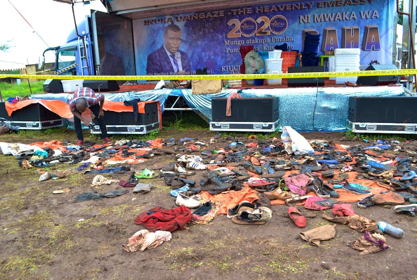 A journalist looks at the abandoned shoes and personal belongings after a stampede, as worshippers rushed to be anointed, during a church service at the Ushirika stadium in Moshi, near Mount Kilimanjaro, Tanzania February 2, 2020.