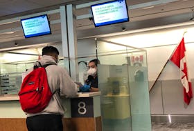 A Canada Border Services Agency (CBSA) officer wears a protective face mask amid coronavirus fears as she checks passports for those arriving at Toronto Pearson International Airport on Sunday, March 15.